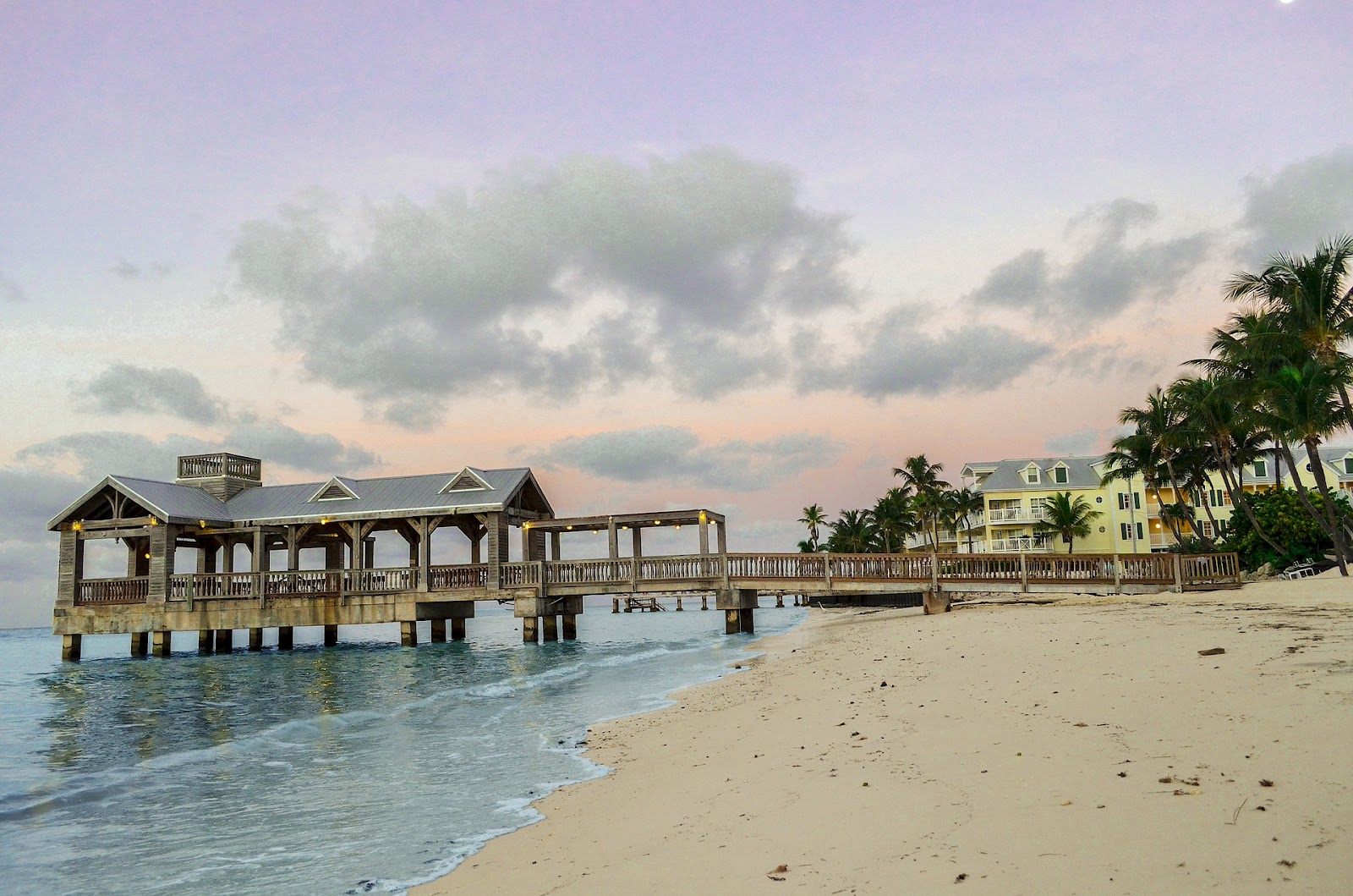 wooden pier near clean sandy beach palm trees and calm blue ocean in key west florida. See it on a road trip with Rentalmoose