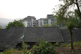 roof of building with traditional Chinese architecture and more modern apartment buildings in the background