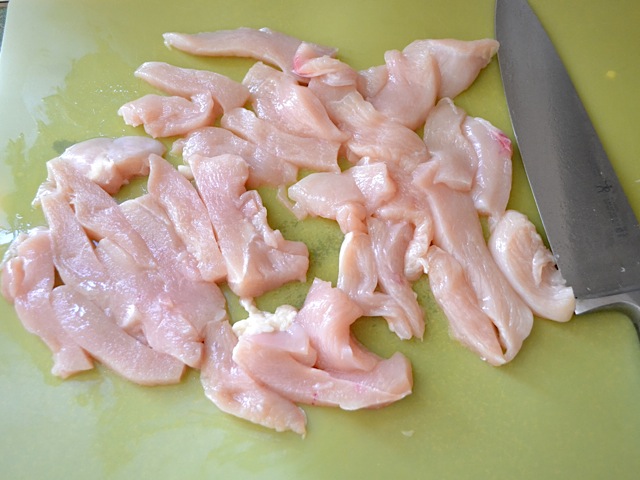 chicken sliced into strips with knife 