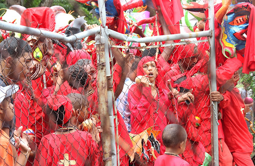 Diablos de Yare apiñados contra una cerca en el día de Corpus Christi en San Francisco de Yare, Municipio Bolivar, Miranda Venezuela
