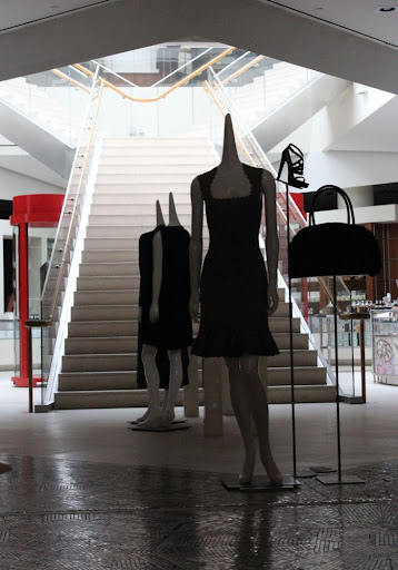 mannequins with pointy necks and no heads, back-lit by a Y-shaped white staircase
