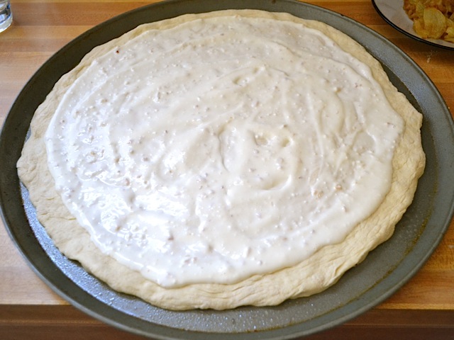 dough placed on pizza pan and sauce spread on top 