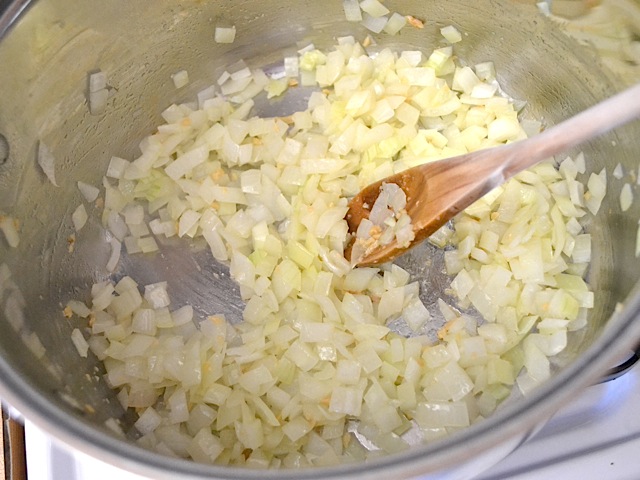cooked onion and garlic in pot with wooden mixing spoon 