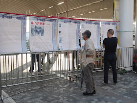 men reading information posted by Hong Kong Alliance in Support of Patriotic Democratic Movements in China