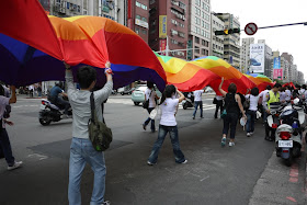 people holding up a large waving rainbow banner