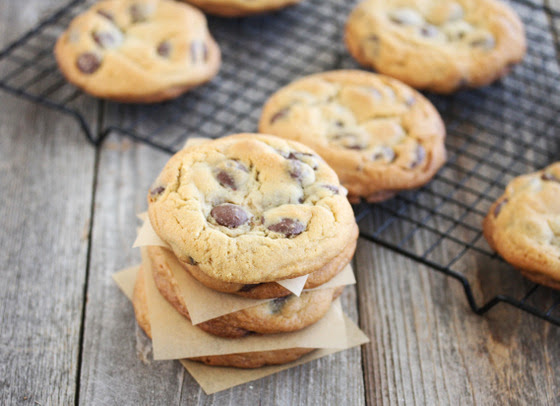 photo of a stack of chocolate chip cookies with cookies on a baking rack in the background
