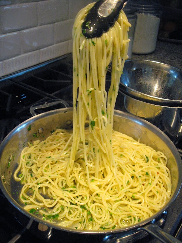 A simple dish of spaghetti with olive oil, garlic, and parsley. We always bring the pasta to the pan with the sauce for the final mixing stage before serving. 