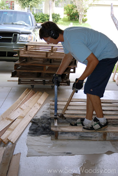 Man removing nails from pallet using a crow bar and hammer. 