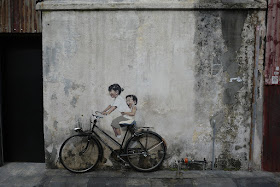 real bicycle against a wall with painted bicycle riders in George Town, Penang, Malaysia