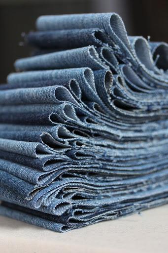 strips of denim cut for a quilt and stacked so the ends roll