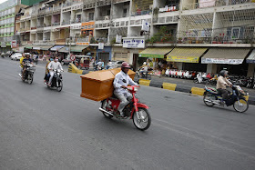 man carrying a coffin on a motorbike