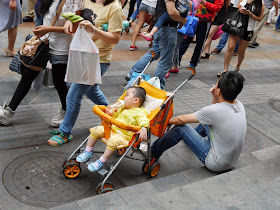 man sitting down and smoking next to a child in a stroller