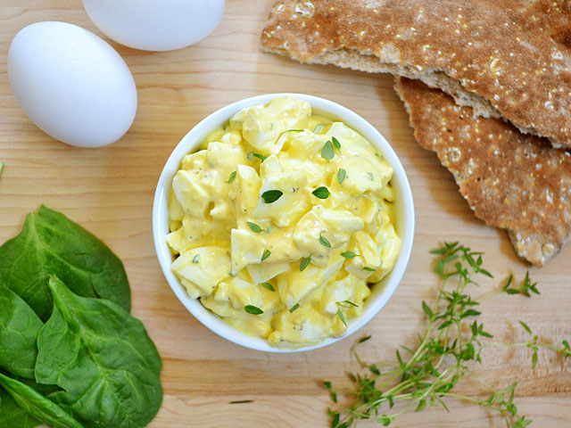 Top view of a bowl of lemon herb egg salad with ingredients staged on the side 
