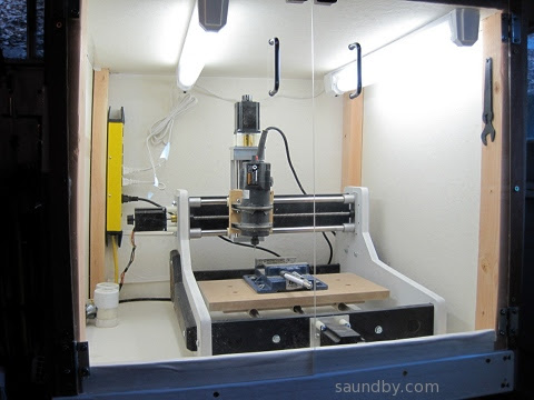 A look inside the CNC enclosure box at the top of the unit, showing the CNC inside with integral lighting and a power bar for the router spindle.