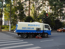 road sweeper truck with the slogan "建设国际静安 创建文明行业" on it cleaning a street in Shanghai