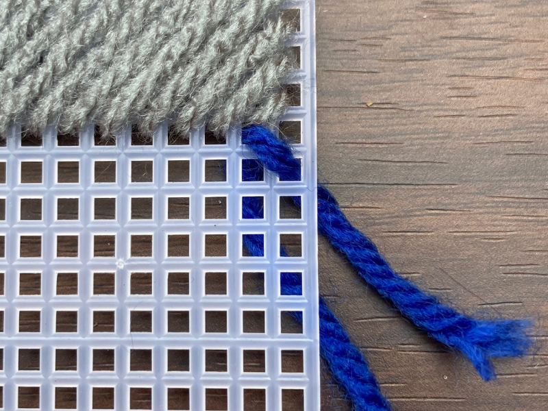 weaving blue colored yarn in plastic canvas 