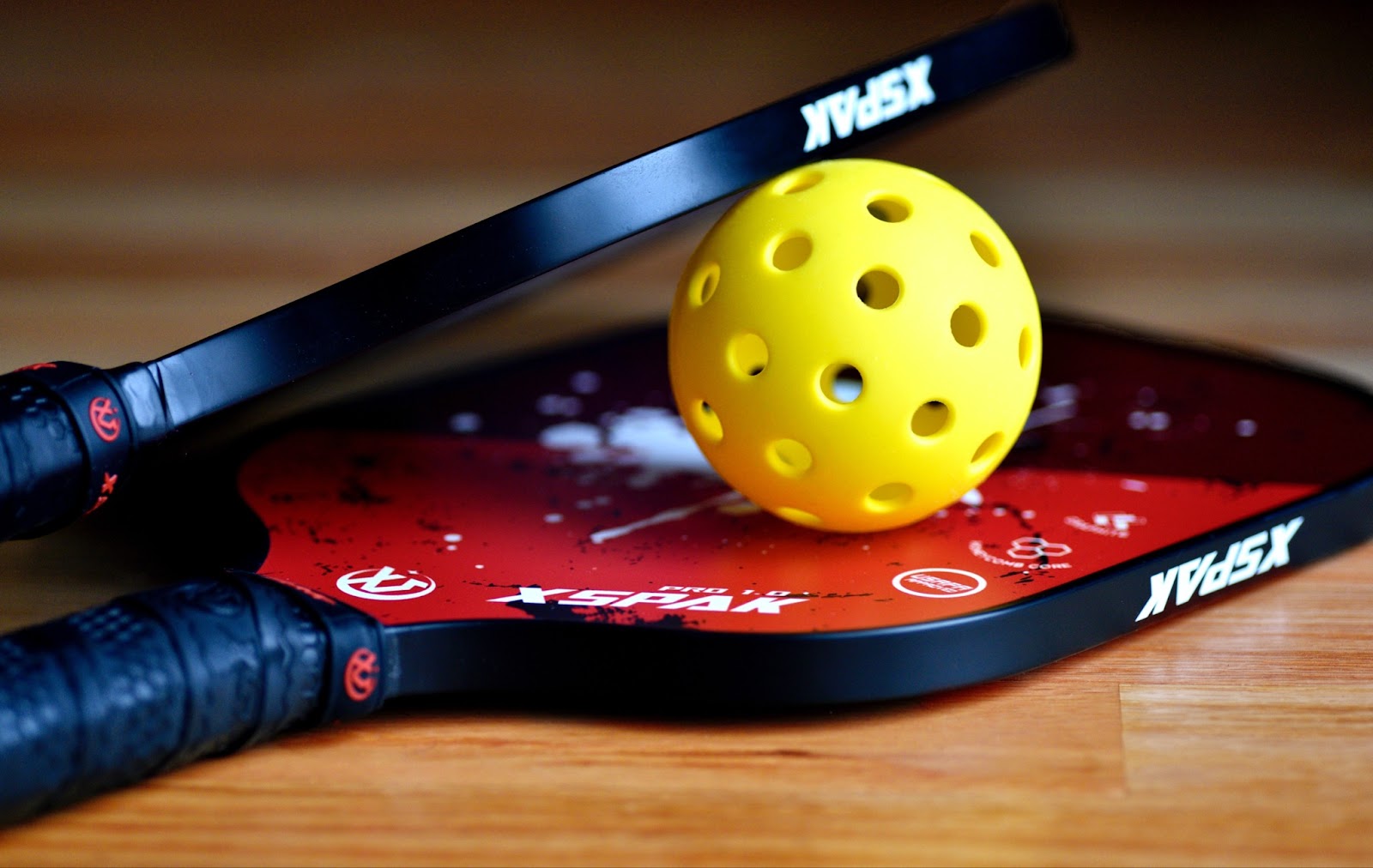 Two pickleball paddles with a pickleball on desk