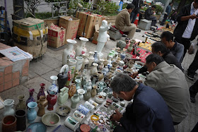 people examing items on the ground for sale outside Tianxinge Antique City in Changsha, China