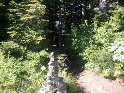 A cairn and sign mark the correct trail branch to follow