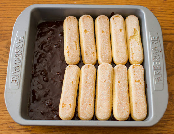 overhead photo of brownie batter and lady fingers in a baking pan