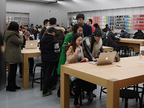 three young women in front of a laptop at Jiefangbei Apple Store in Chongqing on opening day