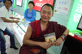 Tibetan monk holding a DVD of the movie Colombiana in Xining, Qinghai, China