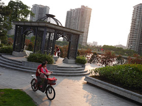 man with a young girl riding a motorbike through a riverside park