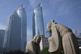 sculpture of traditional scene in front of modern skyscrapers