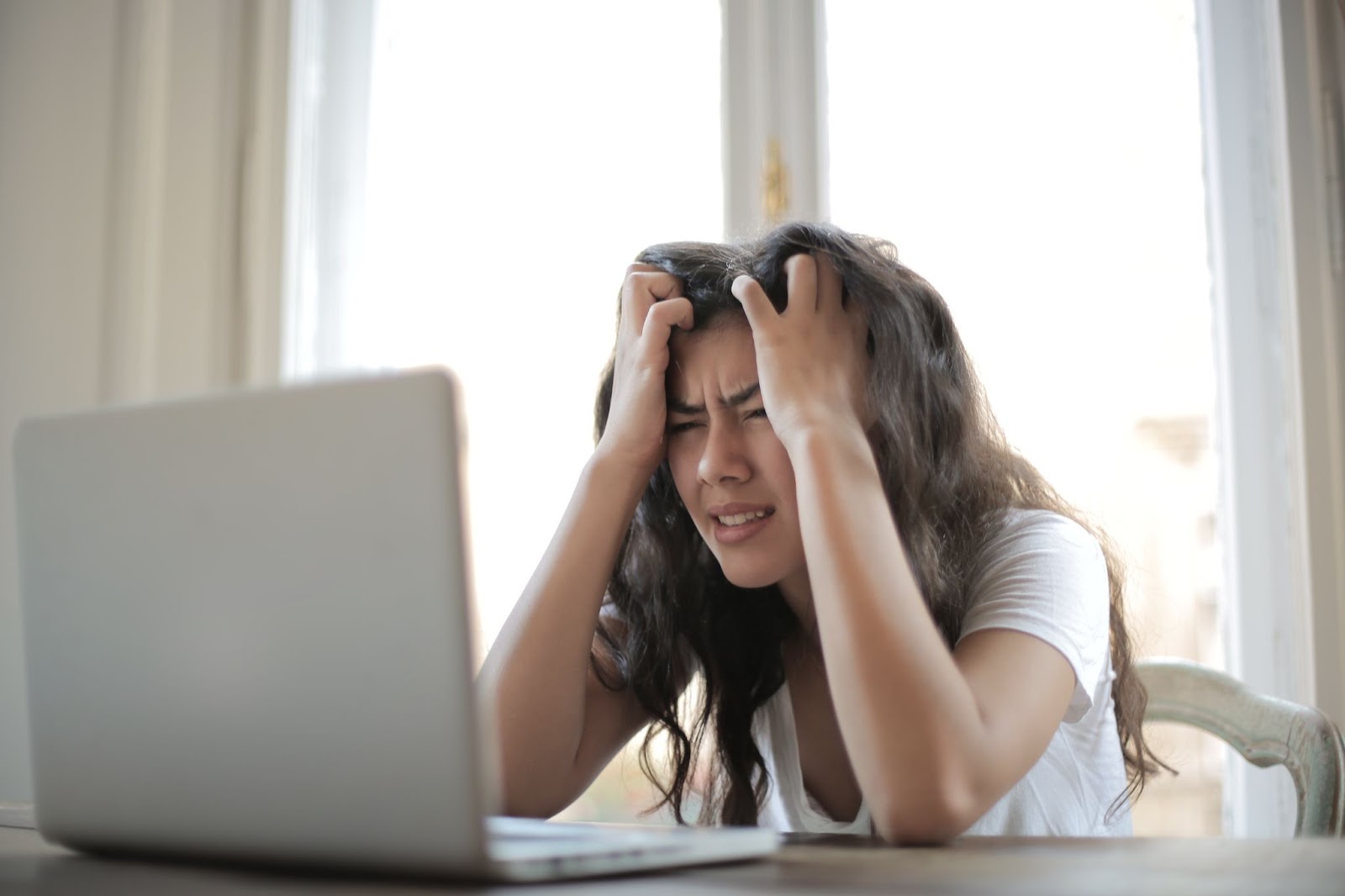 An image of a woman looking frustrated at her laptop.