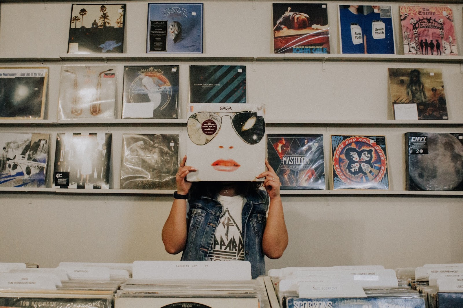 Person in a record store holding record over face