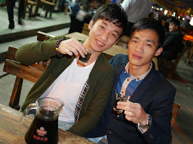 two young men holding shot glasses in Maoming, China