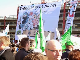 Demonstranten mit Fahnen und Transparent: »Weniger geht nicht!«.