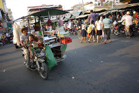 man with child driving a motorbike with a mobile drink cart in Phnom Penh