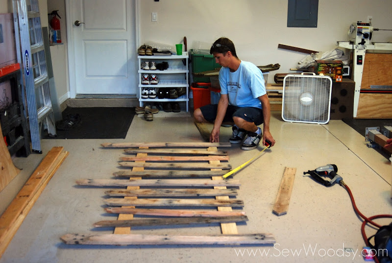 Man measuring a wood fence on a garage floor.