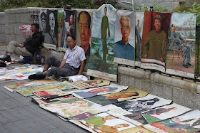 man sitting next to posters, many of Mao Zedong, for sale outside Tianxinge Antique City in Changsha, China