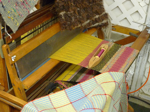With the yarn and thread complete, it's time to weave with it. Here's a great example of a hand operated loom.