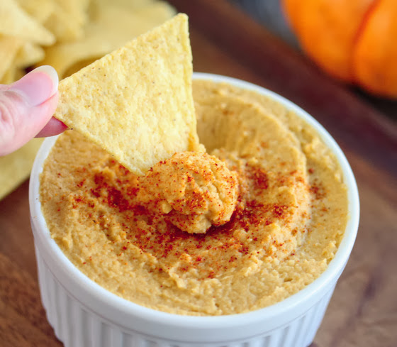 a chip being dipped in hummus.
