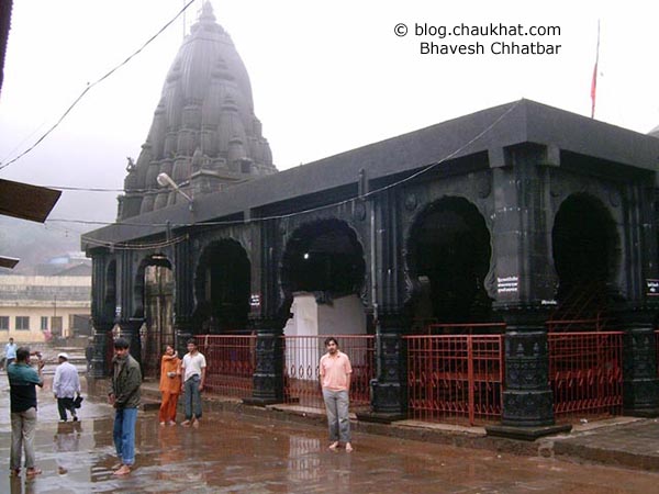 Bhavesh is posing in front of the beautiful black colored temple of Bhimashankar.