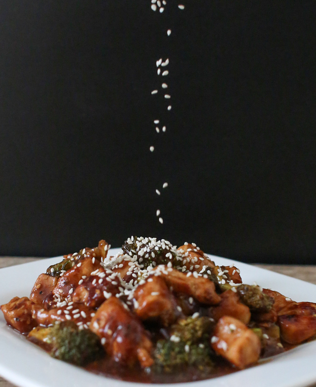 photo of sesame seeds being sprinkled on the sesame chicken dish