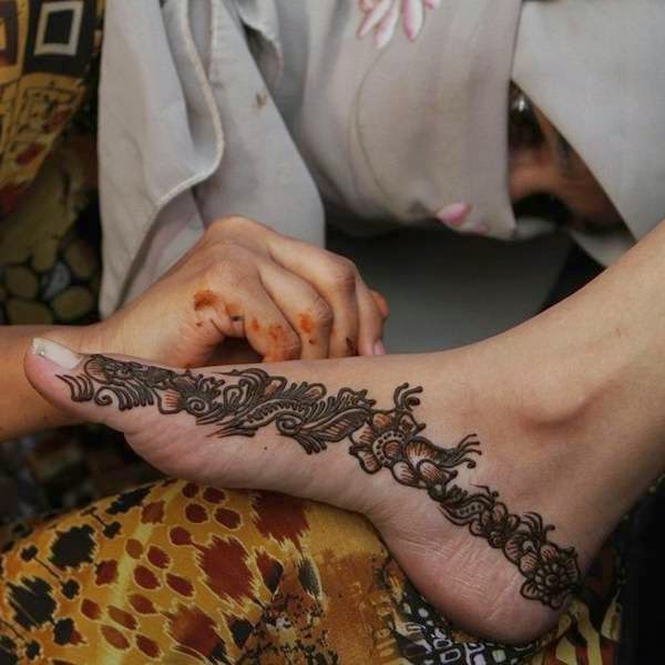 A Pakistani beautician paints a foot of a customer with henna ahead of Eid al-Fitr, in Karachi, Pakistan.