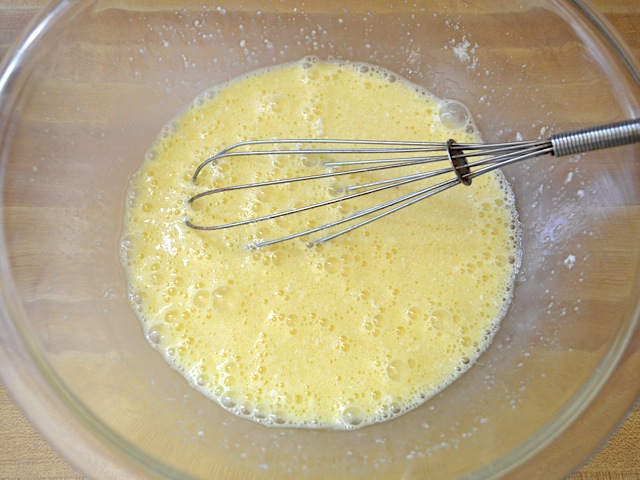 whisked eggs and parmesan in mixing bowl with whisk 