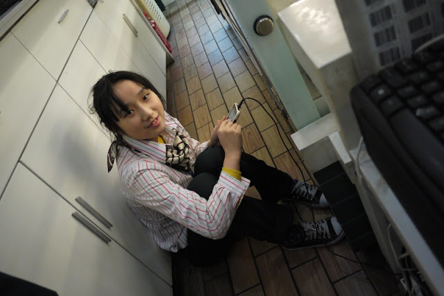 young female sitting on the ground and holding a plugged-in mobile phone