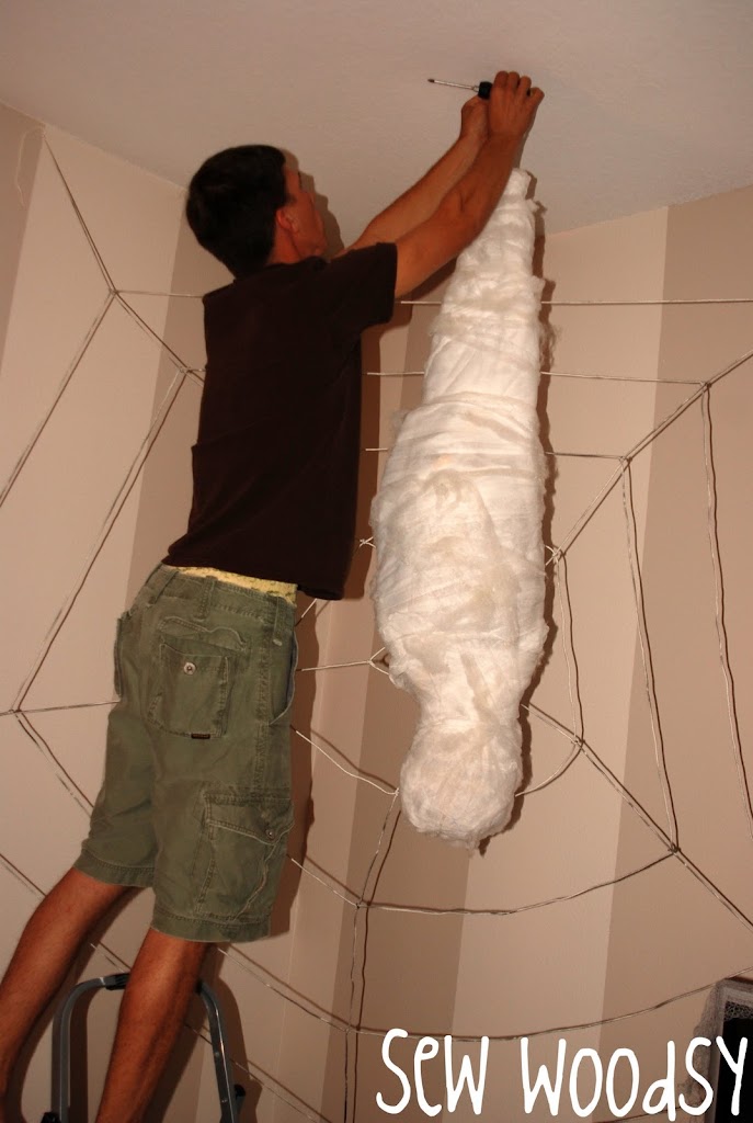 Man hanging a webbed person to the ceiling.