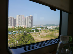 a view of apartment complexes and fields through a train window