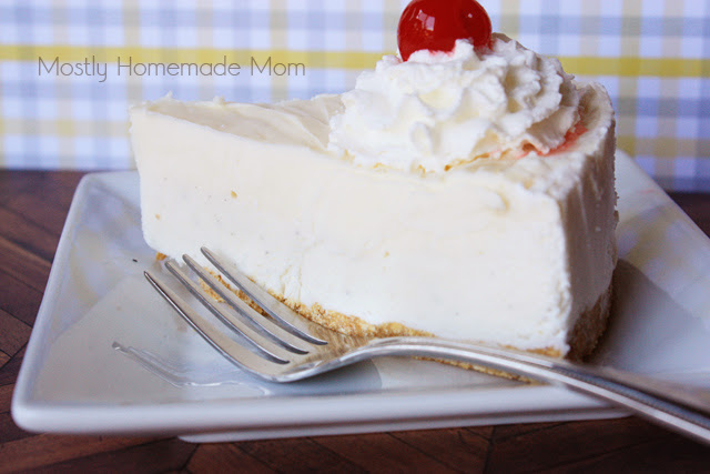A slice of vanilla ice cream cheesecake on a white plate with a fork.