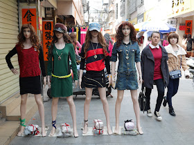 two young women walking by mannequins in Yangjiang, China