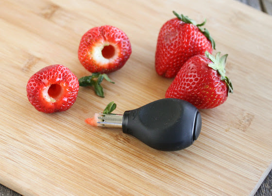 photo of a strawberry huller on a board with fresh strawberries
