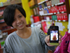 young woman holding a Nokia phone displaying a closeup photo of a chicken directly facing the camera