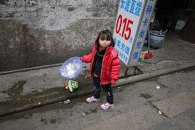 little girl holding a small container of trash in Guangzhou, China