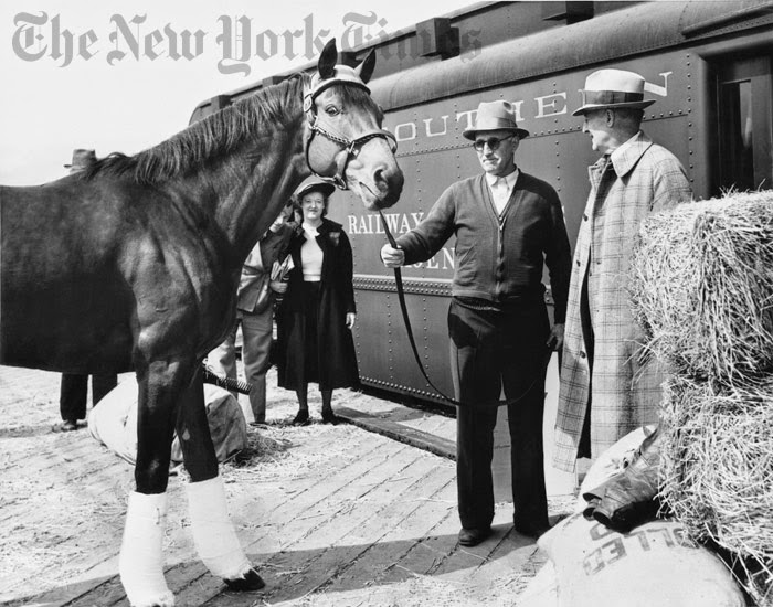 Seabiscuit com seu treinador Tom Smith, segundo da direita, e seu proprietário, Charles S. Howard, à direita, em seu caminho para competir com War Admiral em 1938.